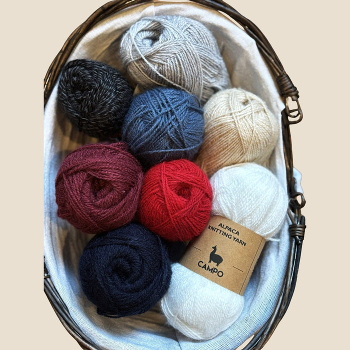 Basket with various colored yarn balls and a 'Campo' label on a beige background