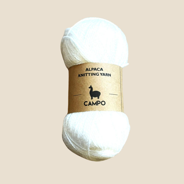 Ball of white yarn with a brown label on a beige background