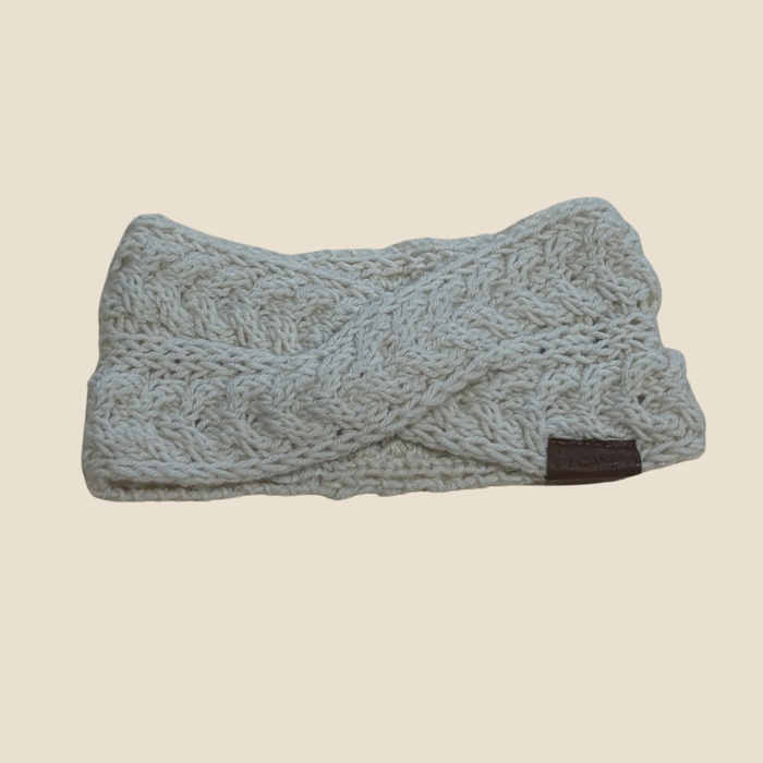 Knitted headband with braided pattern on a beige background