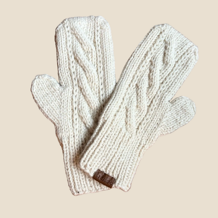 Pair of cream-colored knit mittens on a wooden surface