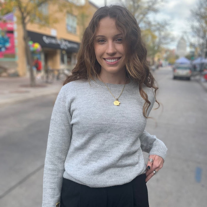 Woman in a light gray sweater standing on a street