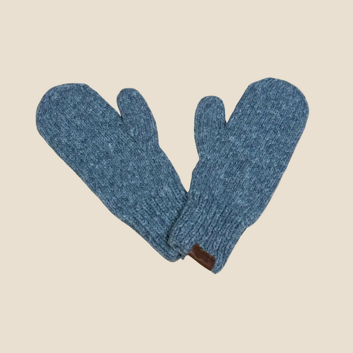 A pair of heathered blue knit mittens crossed over each other on a solid pale beige background.