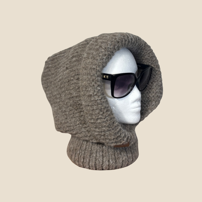 Brown knitted balaclava on a mannequin head with sunglasses, against a beige background