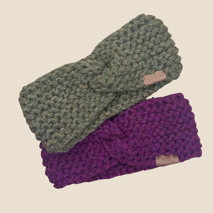 Two knitted headbands, one olive  green and one purple, on a beige background.