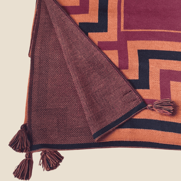 Tiera textured blanket with tassels on a geometric patterned surface