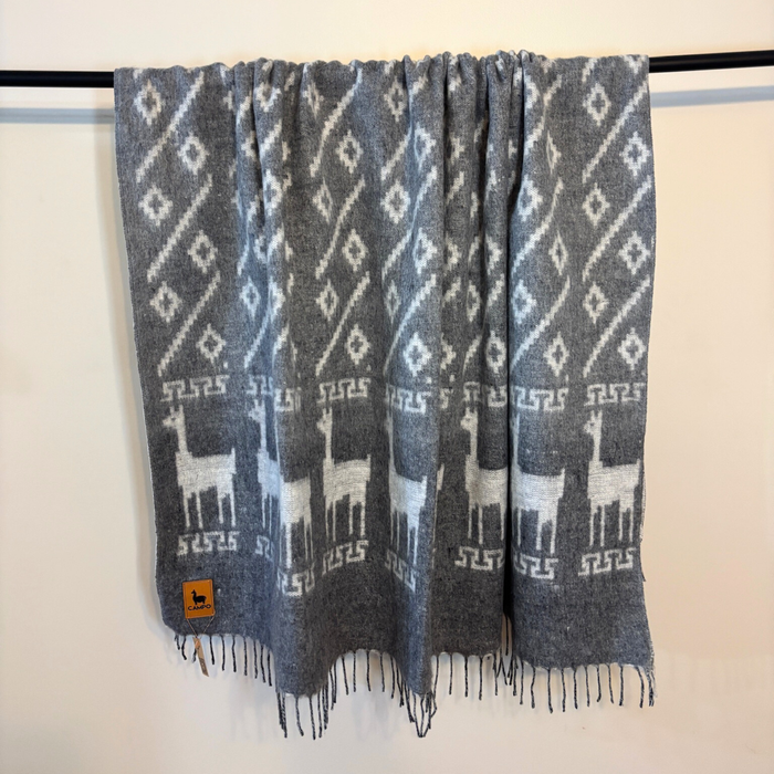Gray patterned scarf with alpaca design hanging on a rack against a white background