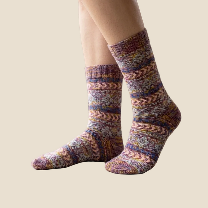Multicolored patterned socks worn by a person on a neutral background