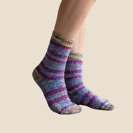 Multicolored striped socks on a person's feet with a light background