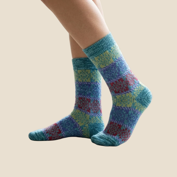 Colorful patterned socks worn indoors on a light wooden floor.