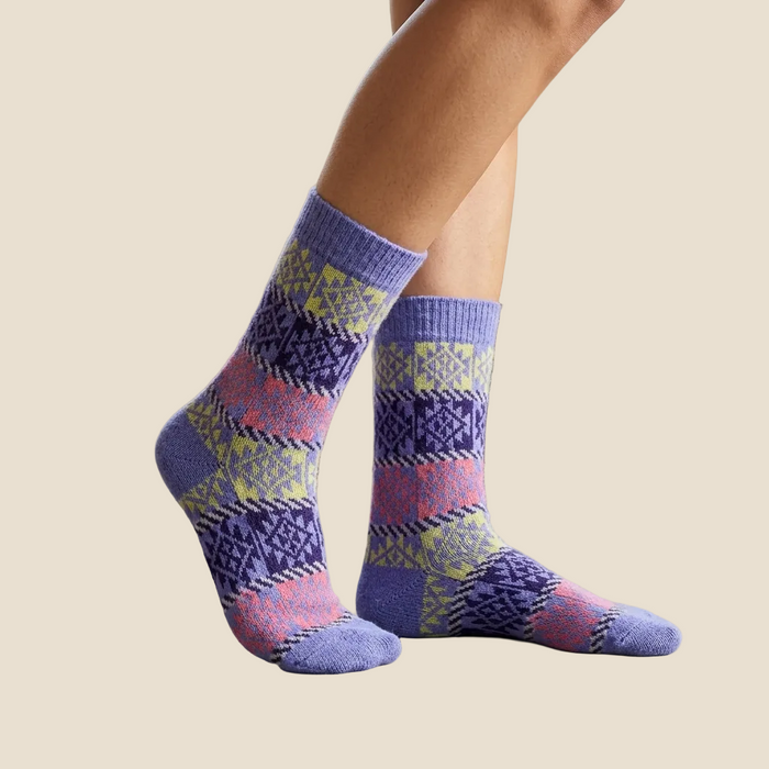 Person wearing patterned socks in a home setting with a chair and table.