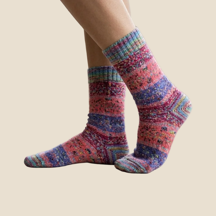 Colorful striped socks worn indoors on a light wooden floor.