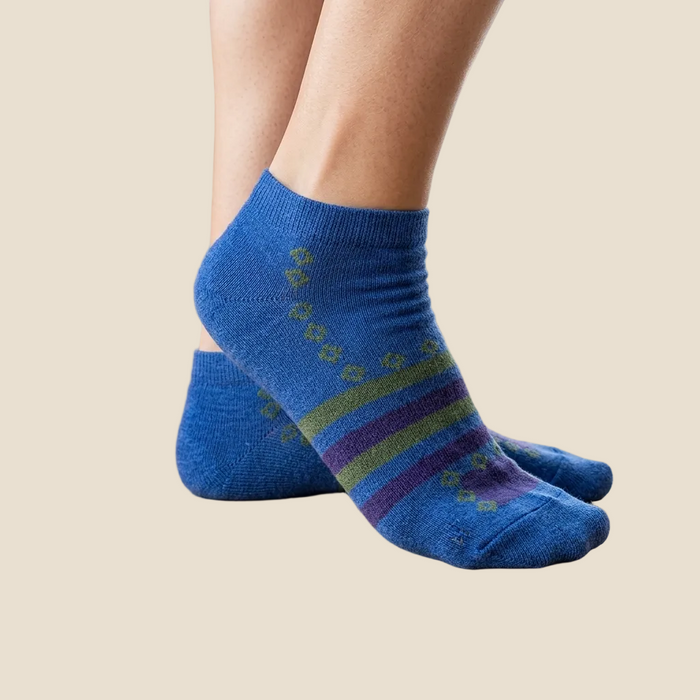 Blue patterned socks worn on a wooden floor with plants in the background