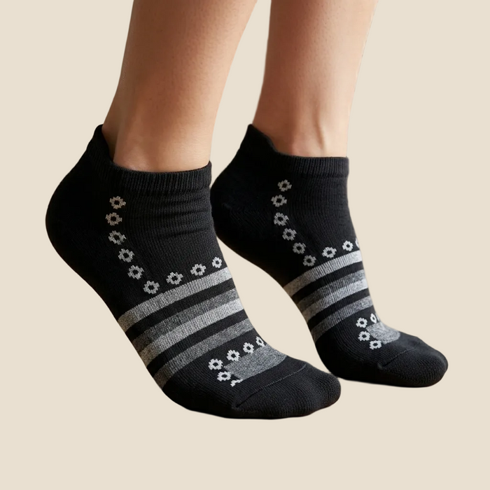 Black socks with gray stripes worn by a person on a wooden floor.
