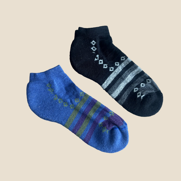 Pair of blue and black ankle socks with patterns on a beige background