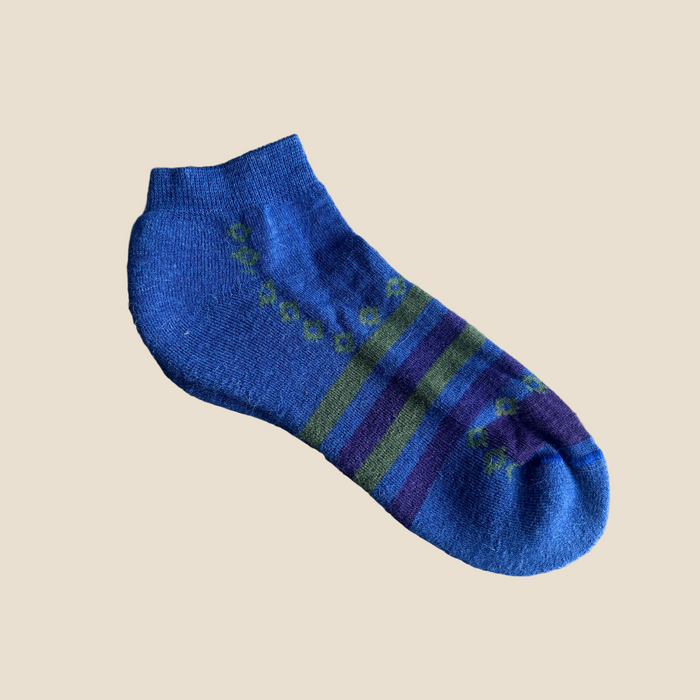 Blue sock with green and purple stripes on a beige background