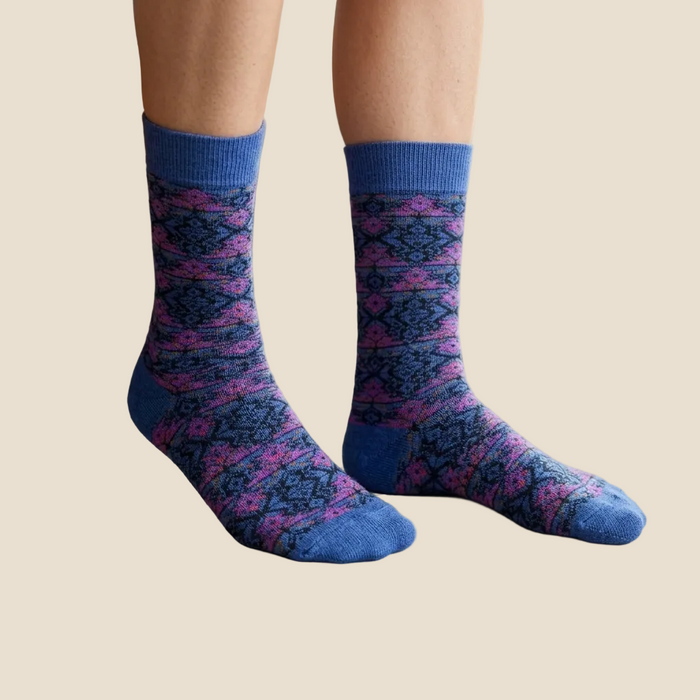 Person wearing blue and pink patterned socks on a light-colored floor.
