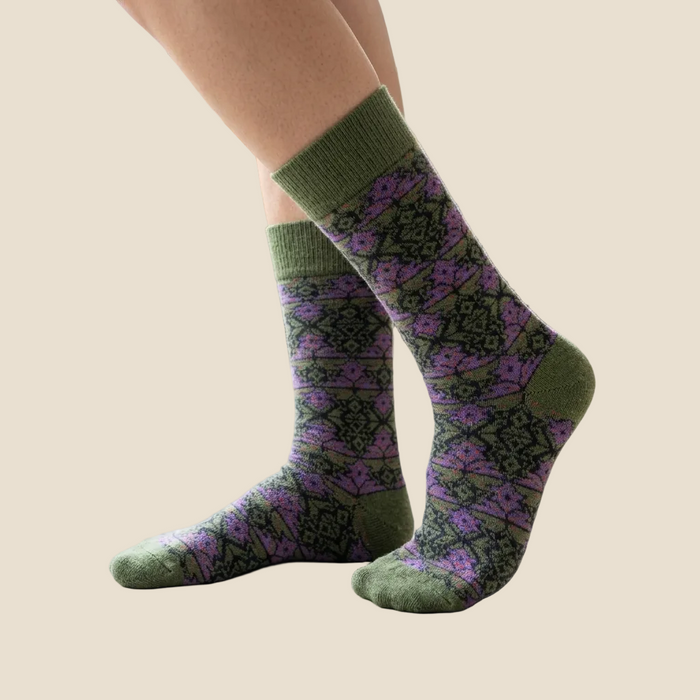 Green and purple patterned socks worn by a person indoors.