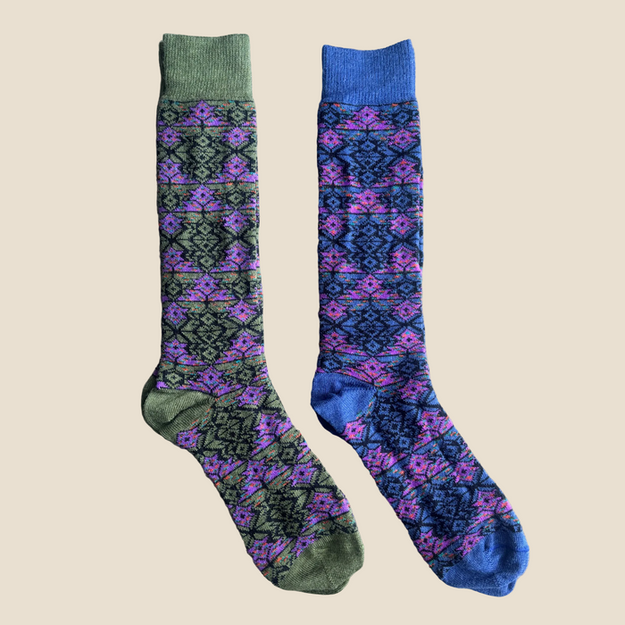 Pair of patterned socks with green and blue cuffs on a beige background