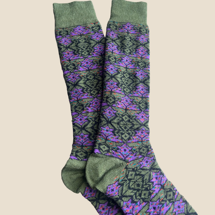 Green and purple patterned socks on a wooden floor