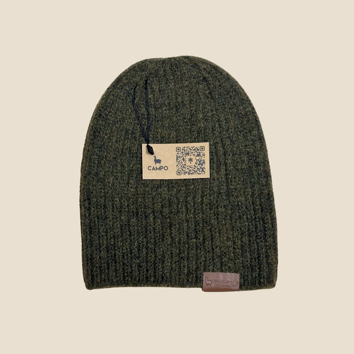 Green knit beanie with a brand label on a beige background