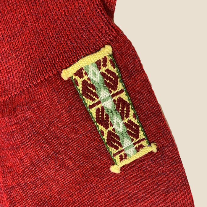 Close-up of a red fabric with a patterned label on a beige background