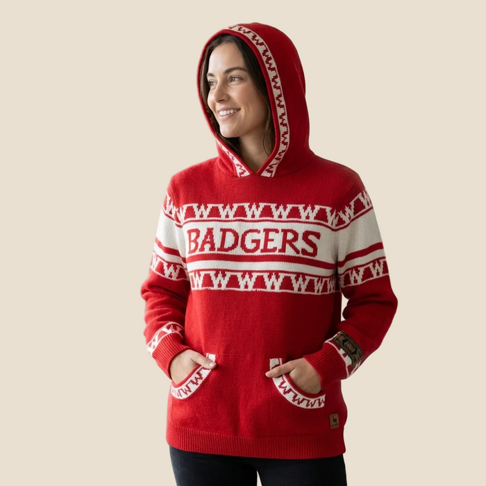 A woman wearing a red knit hooded sweater with white patterned bands and the word 'BADGERS' across the chest, posed against a plain beige background.
