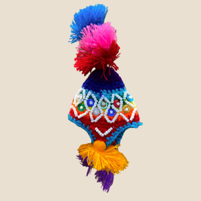 Colorful knitted hat with pom-poms on a beige background