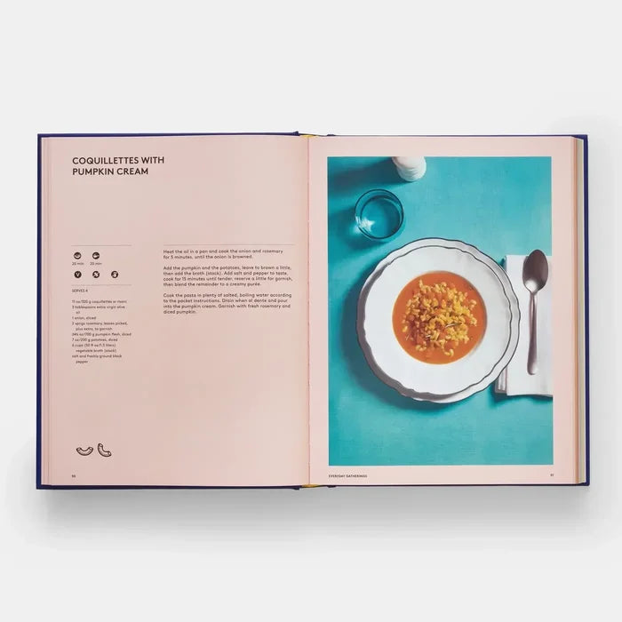 front open cookbook displaying Coquillettes with Pumpkin Cream recipe and plated dish on blue background
