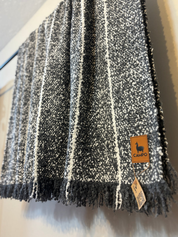 Black and white striped scarf with a brand tag on a neutral background