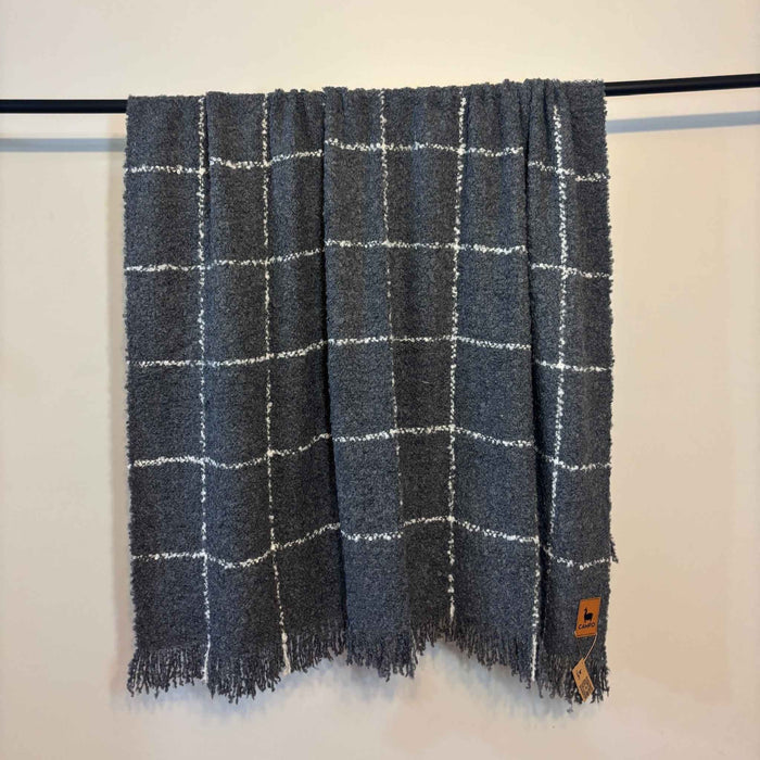 Plaid blanket with white lines on a black rod against a white background