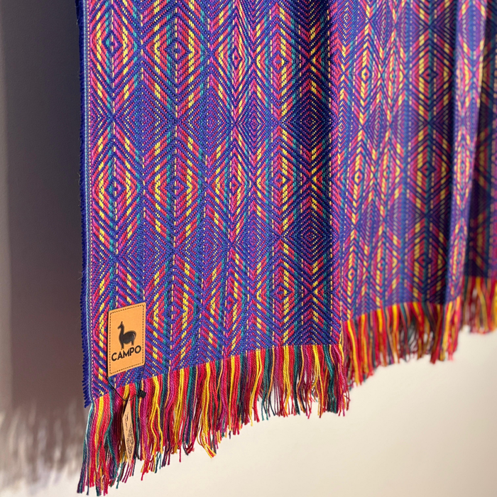 Colorful woven fabric with geometric pattern and 'Camilo' brand label on a neutral background
