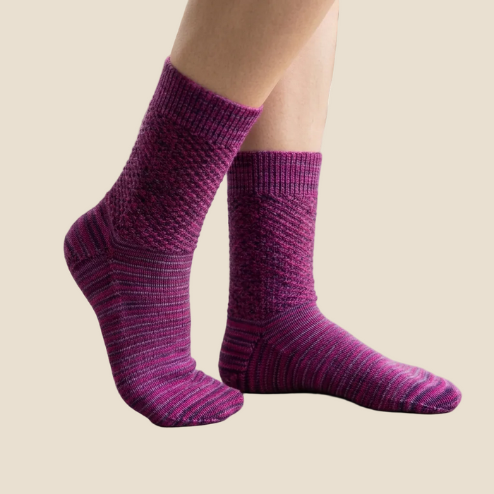 Purple socks worn by a person on a concrete floor with a blurred background