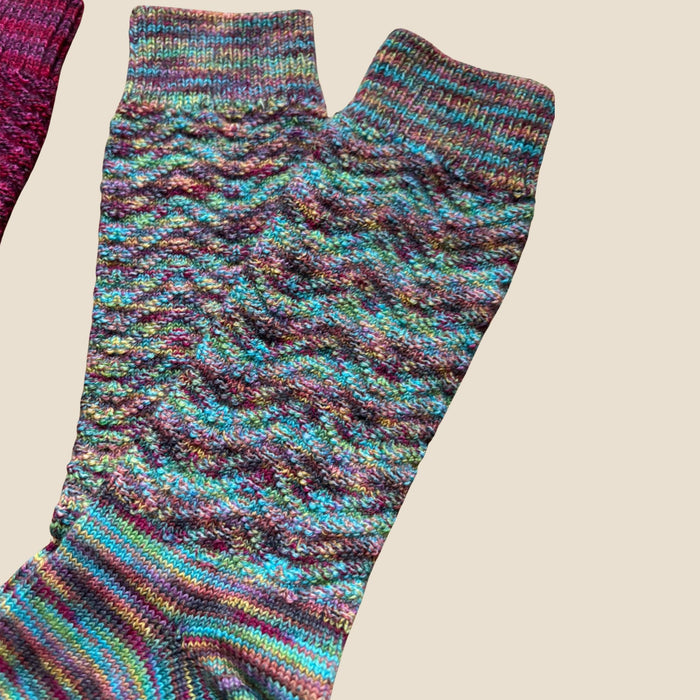 Multicolored knitted sock on a beige background