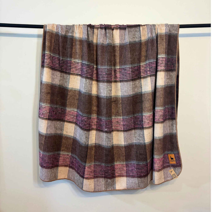 Plaid blanket draped over a rack against a white wall