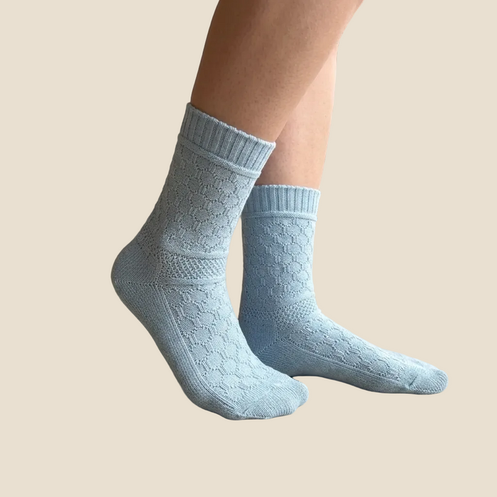 Light blue patterned socks worn by a person on a beige background