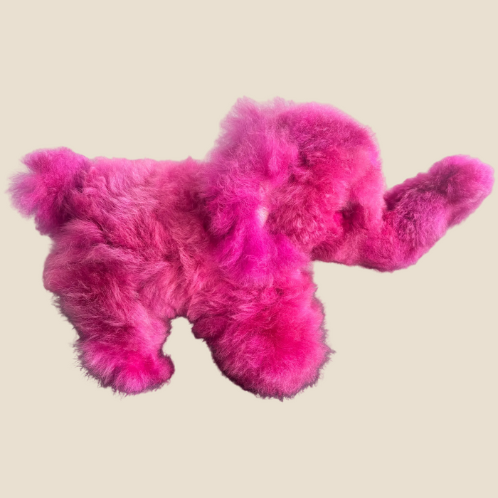 Pink fluffy dog-shaped toy on a beige background