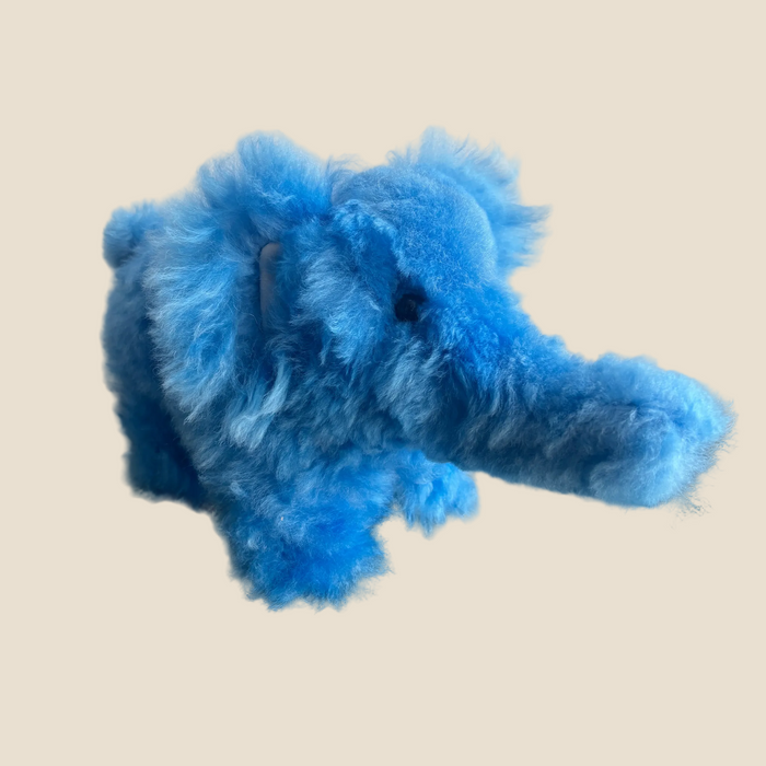 Blue plush elephant toy on a dark surface with a light background
