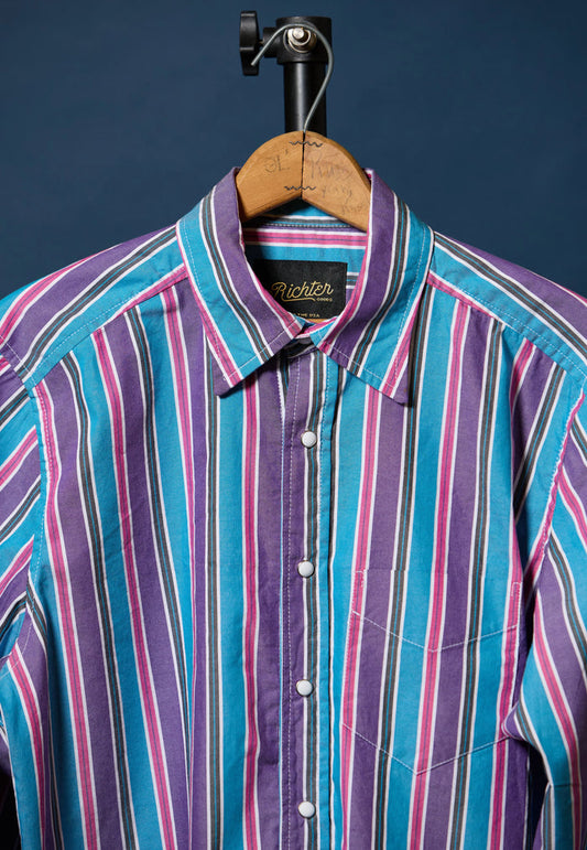 Colorful striped shirt on a hanger against a dark background