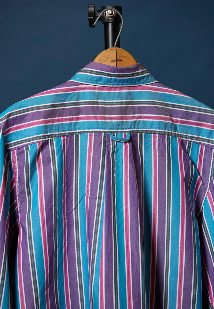 Multicolored striped shirt on a hanger against a dark background