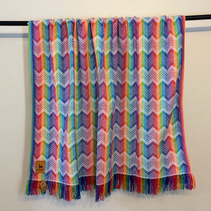 Colorful chevron patterned throw blanket with fringes on a white background