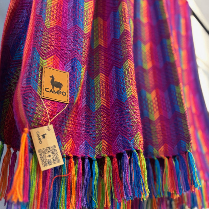 Colorful woven blanket with tassels and a 'Campo' brand tag.