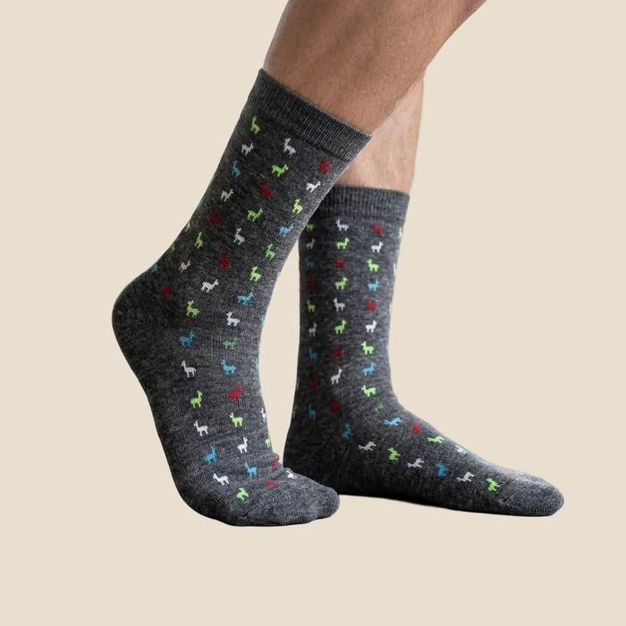 Gray socks with colorful dog patterns worn indoors on a light wooden floor.