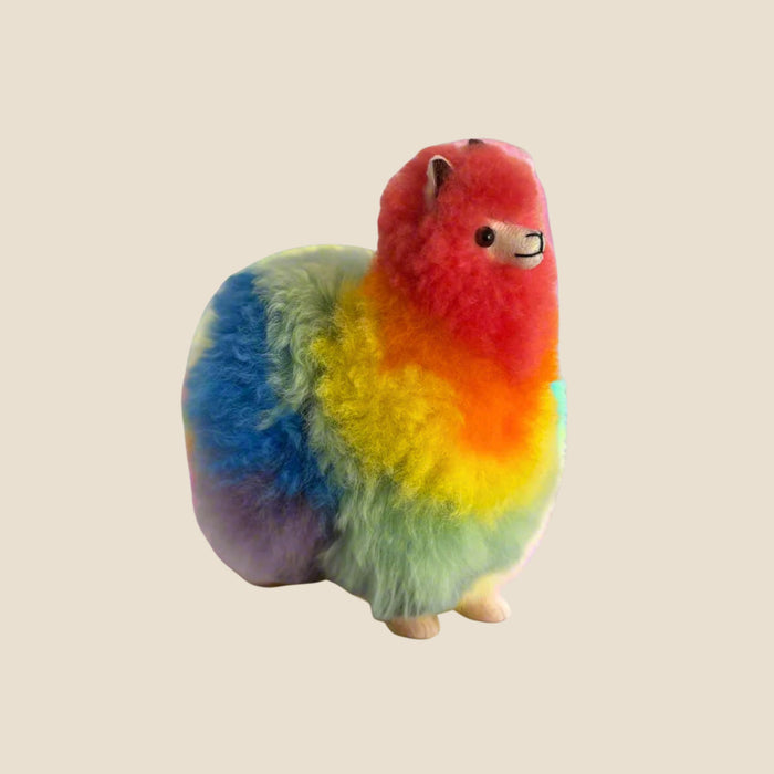 Colorful plush toy resembling a alpaca on a beige background