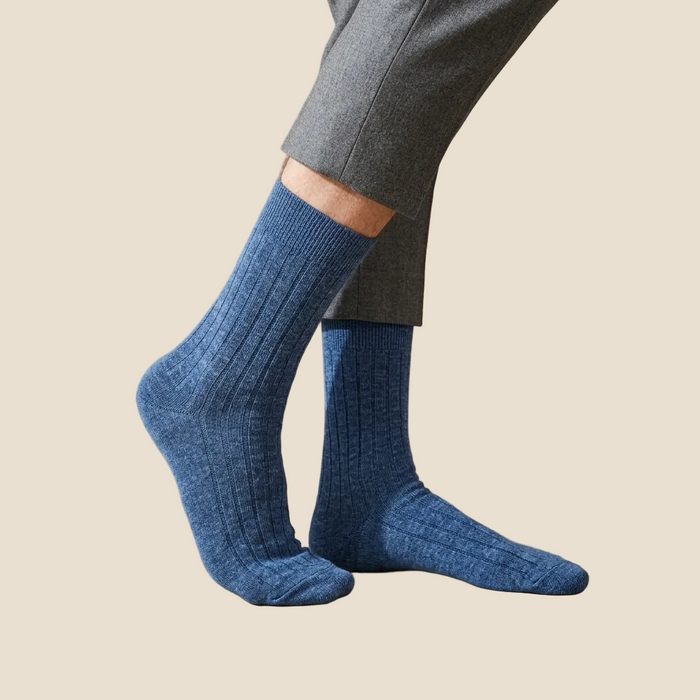 Blue socks worn with gray pants on a beige background