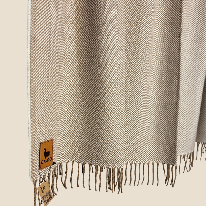 Textured fabric with herringbone pattern and fringes, featuring a brand label.