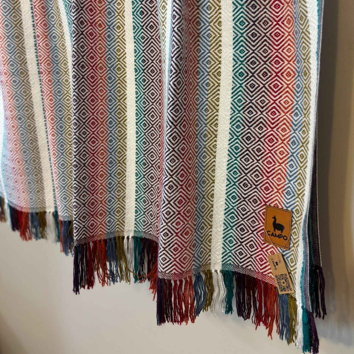 White multi woven fabric with geometric pattern and fringes, featuring a brand tag.