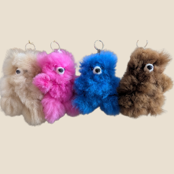 Four colorful plush toys hanging against a beige background