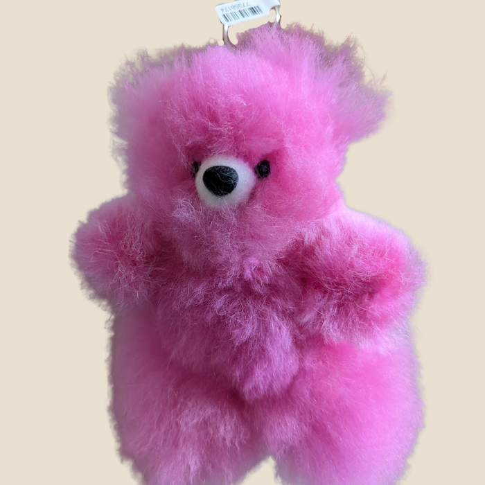 Pink teddy bear with a tag on a beige background