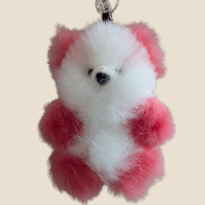 Fluffy red and white bear-shaped keychain on a beige background