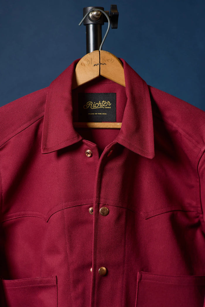 Rhubarb Red jacket on a hanger with 'Richter' label against a blue background